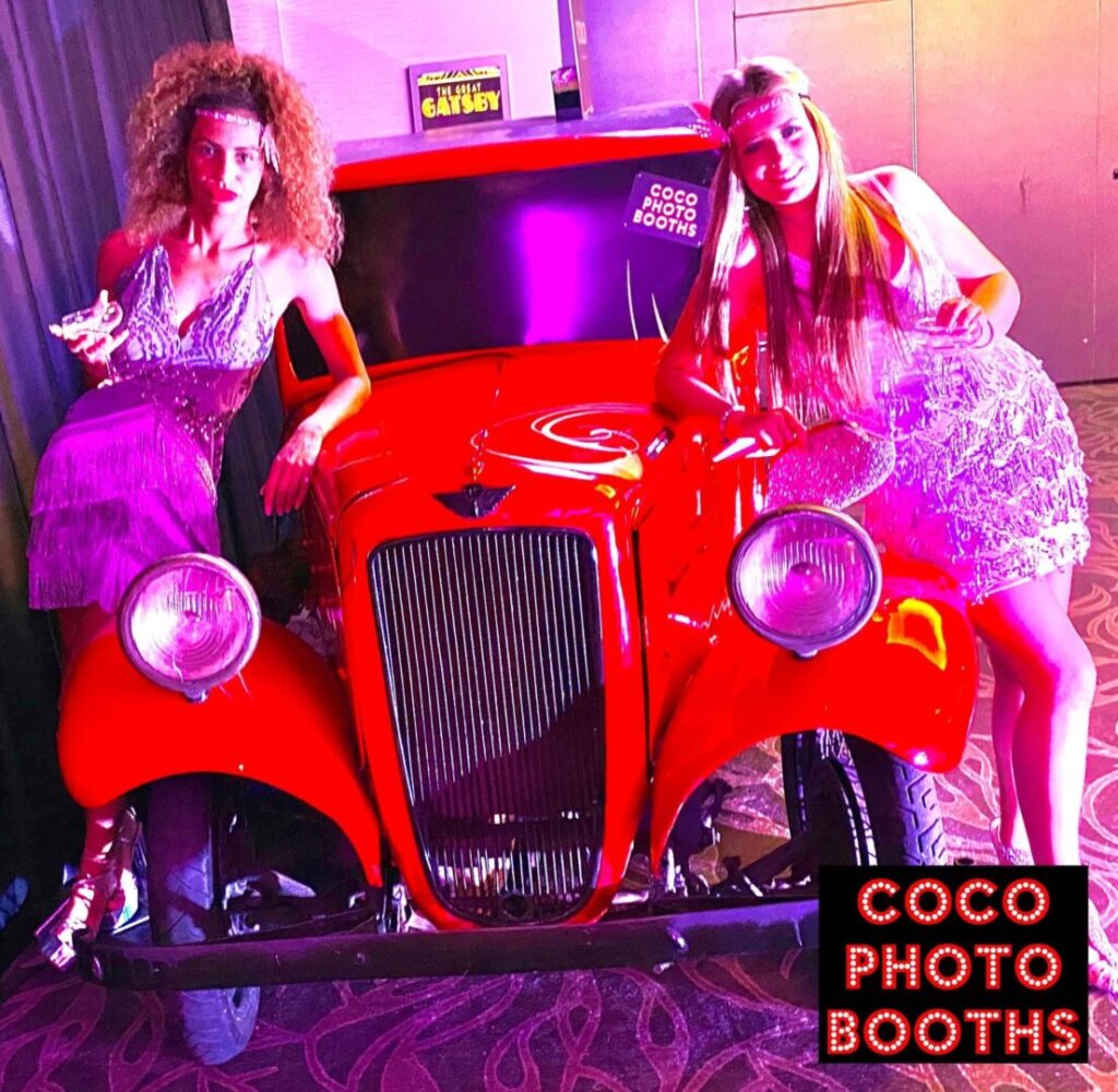 two girls posing with a vintage car photo booth at an event London