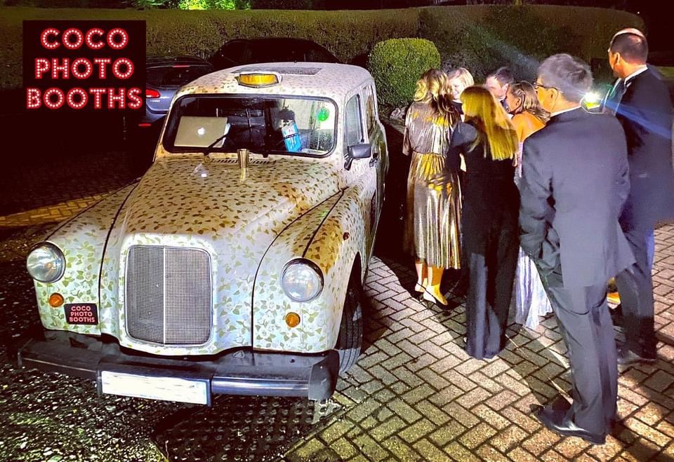 people outside a white taxi photo booth at a party